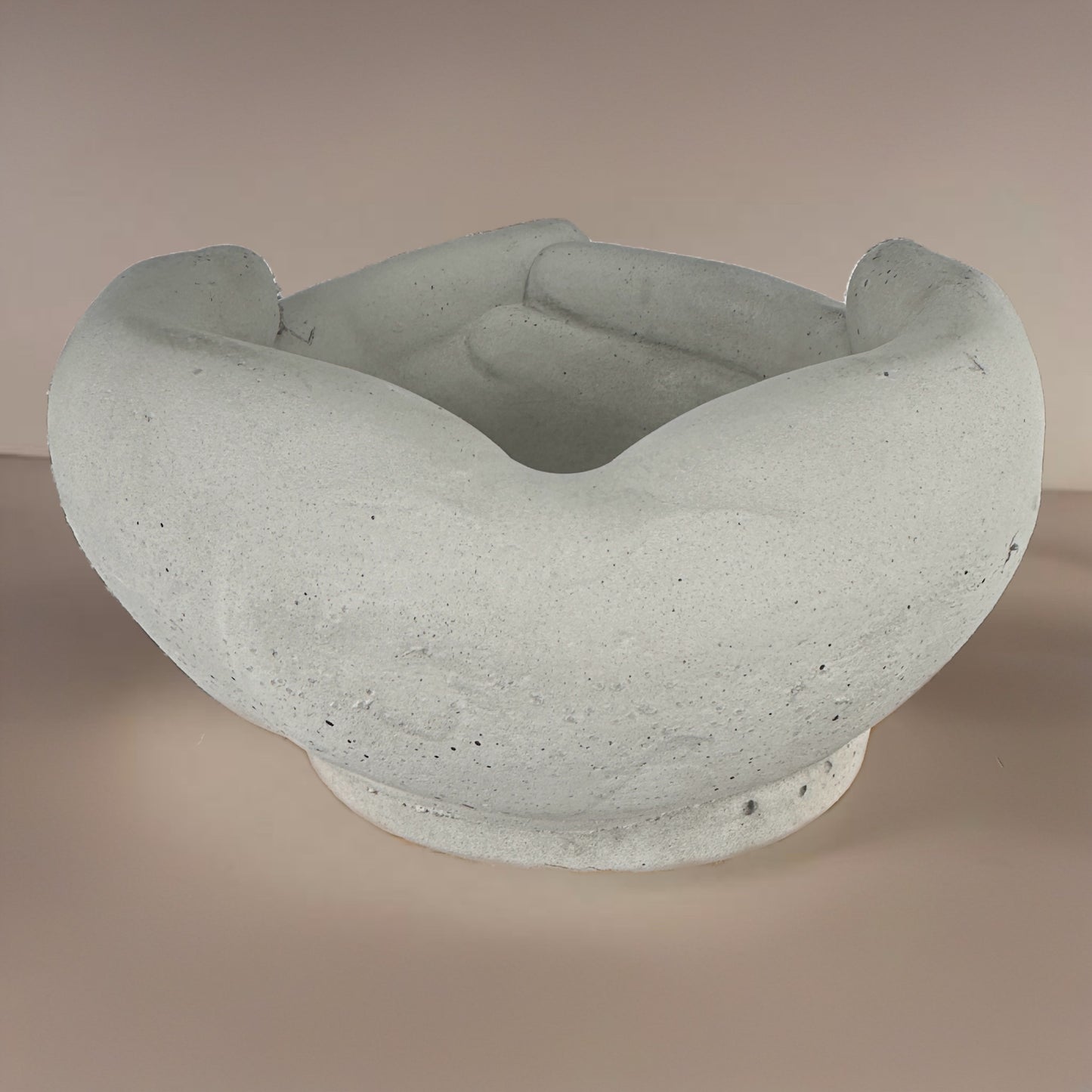 Back angle of a concrete pot shaped like interlocked hands, showing the smooth rear curvature and joined fingertips design
