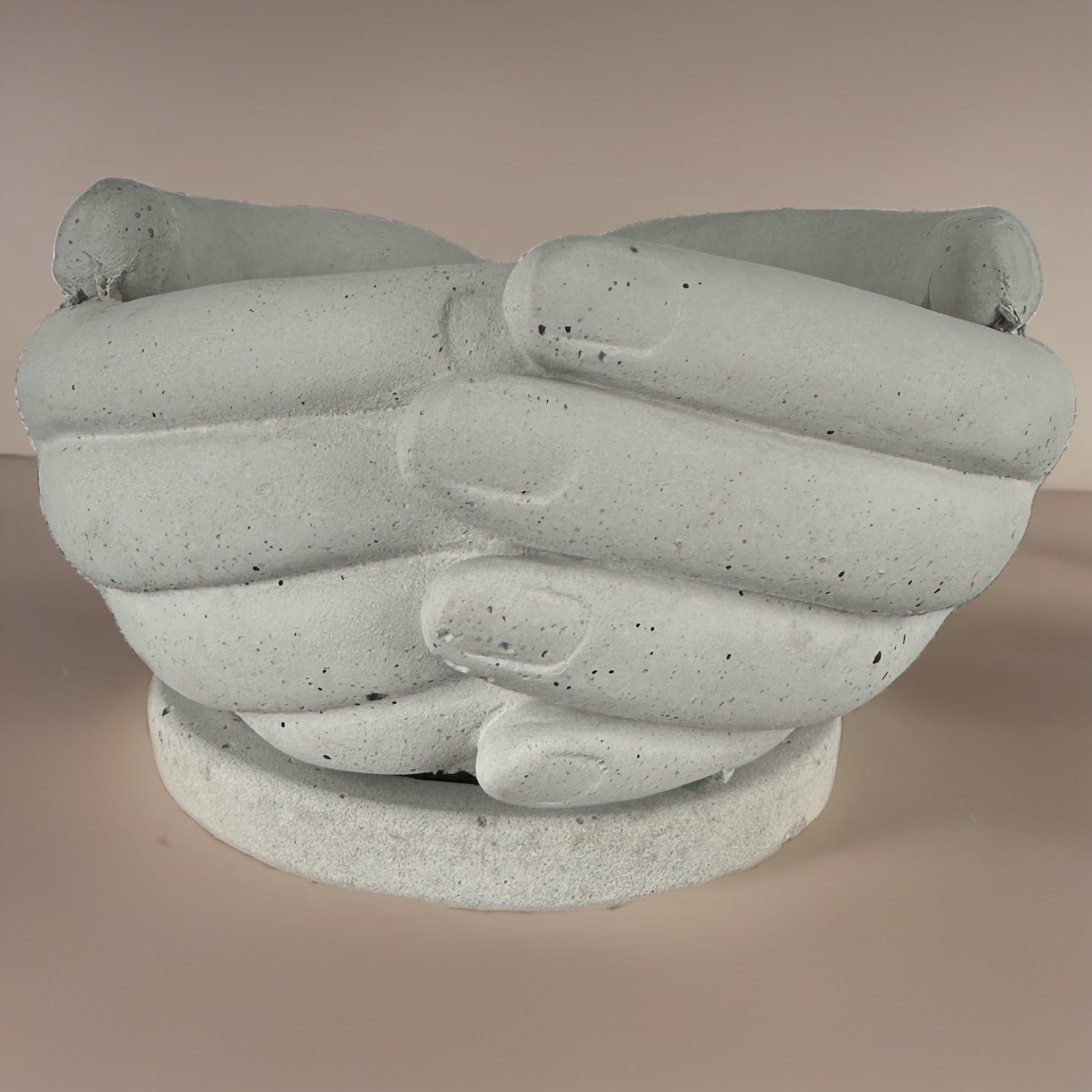 Sculpted concrete planter shaped like two hands holding each other, front-facing view